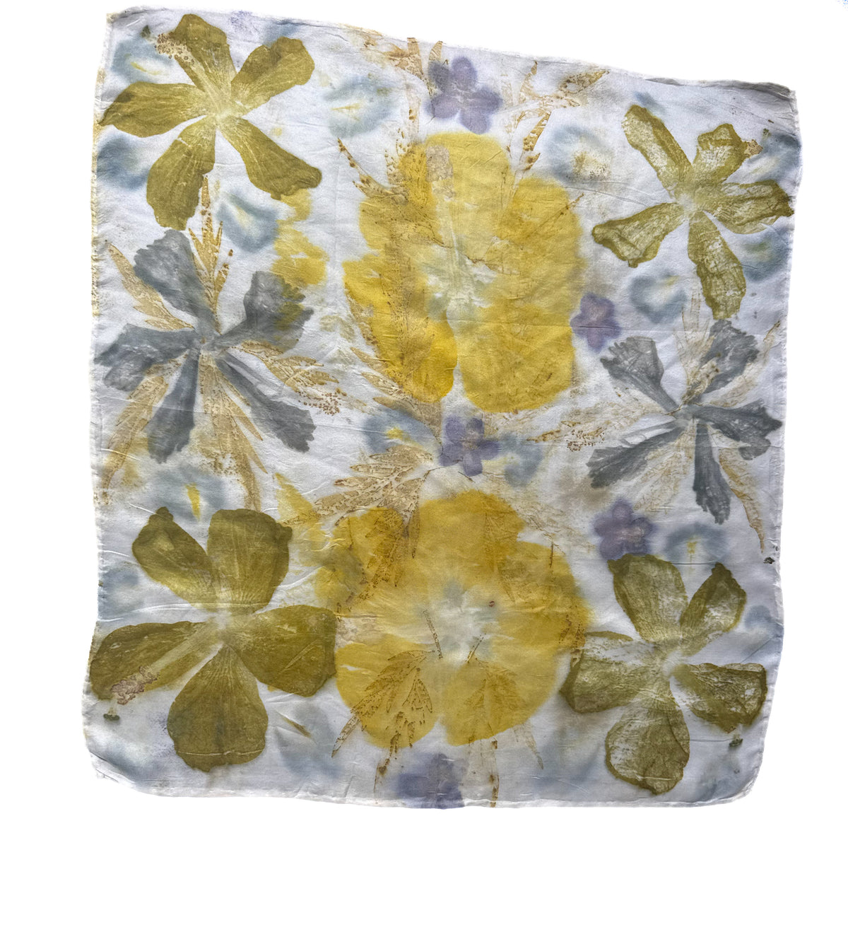 A square handmade paper or fabric art piece featuring pressed floral motifs in yellow, olive green, and lavender-blue on a white textured background.