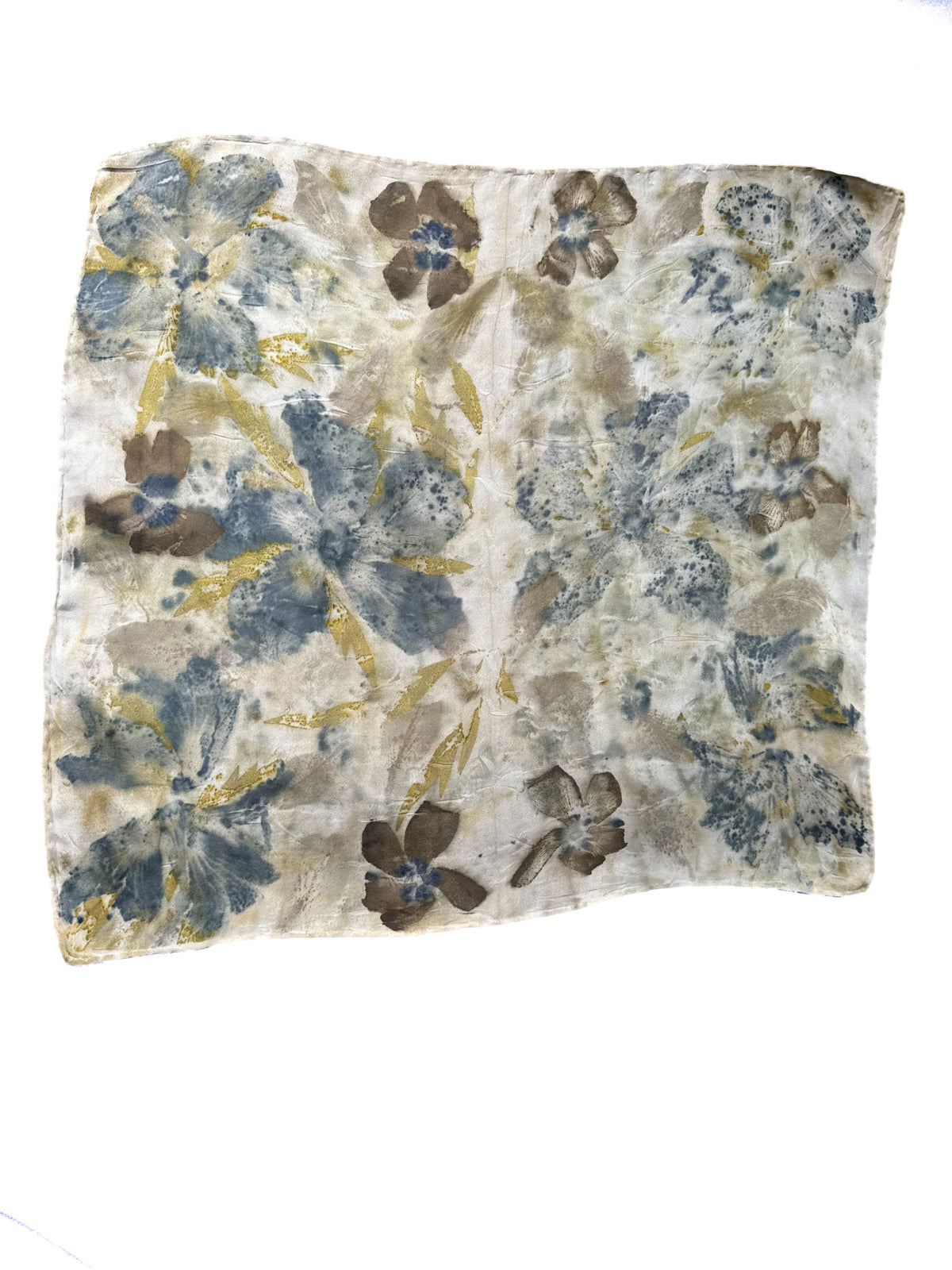 A square scarf with a distressed floral pattern in muted blue, brown, and gold tones on a cream background, shown flat against a white background.